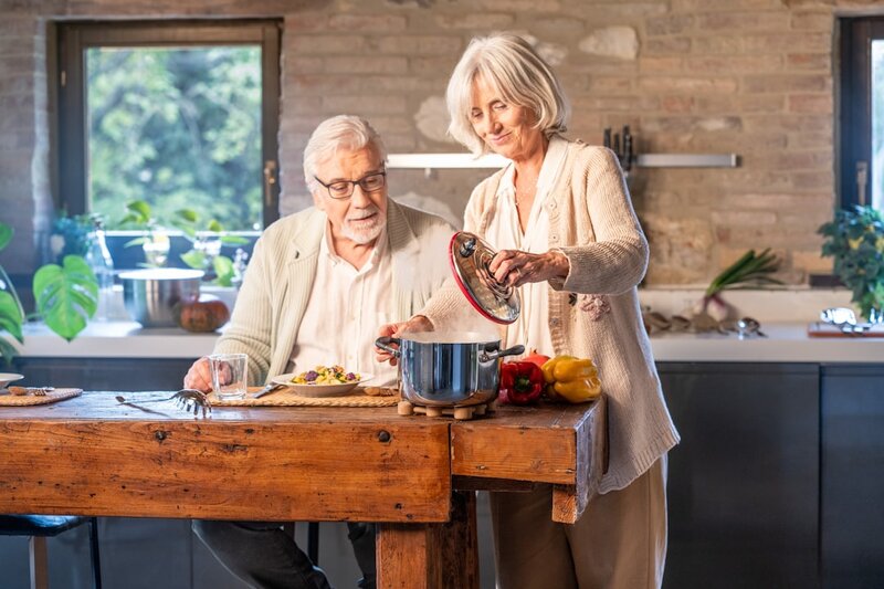 Older couple cooking healthy vegetables together in a kitchen