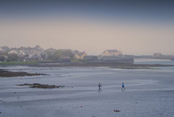 Two people walking along a misty beach by the sea
