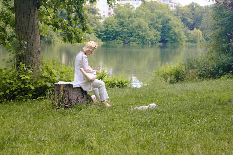Person sitting peacefully beside a lake, representing calm and mindfulness after 50