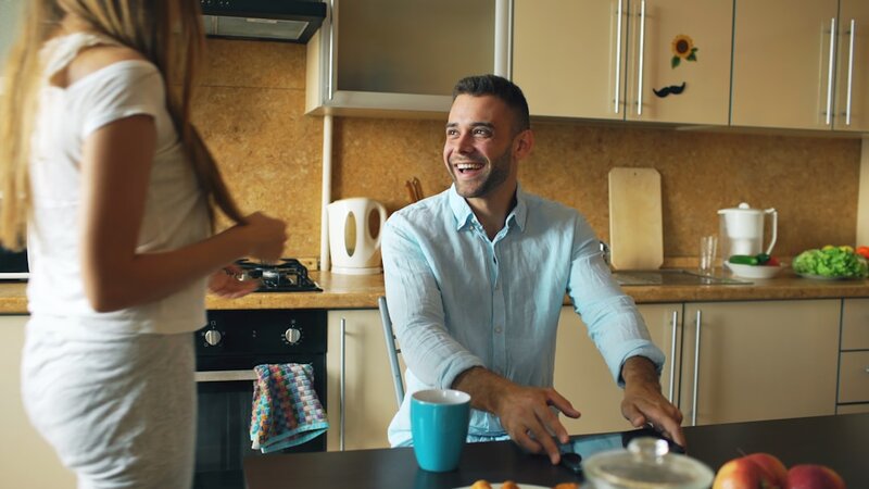 Two people talking together in a kitchen at home