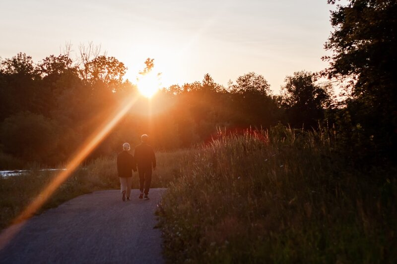 Two people walking together along a countryside path at sunset