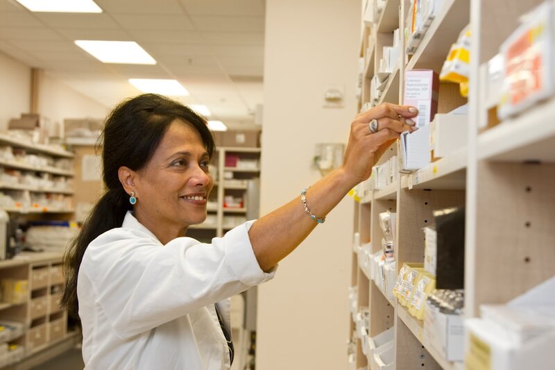 A pharmacist holding a box of medicine at a pharmacy counter