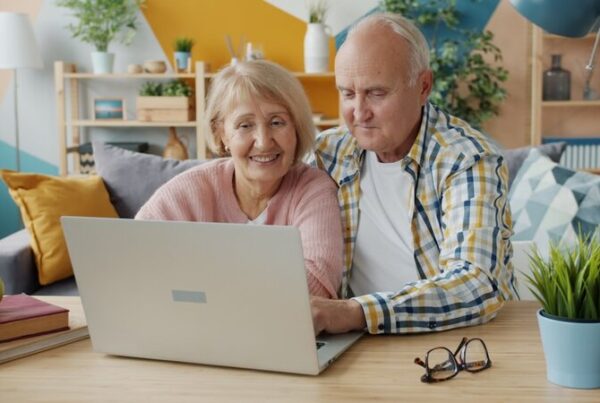 An older couple smiling while looking at a laptop together at home