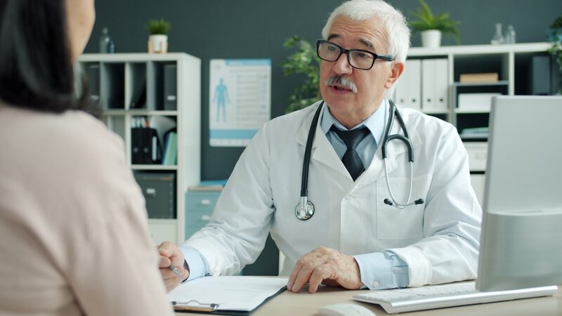 An older man in conversation with a doctor in a consultation room