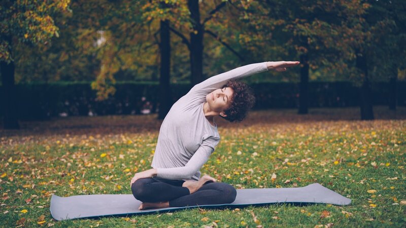 Woman stretching on a yoga mat in a park