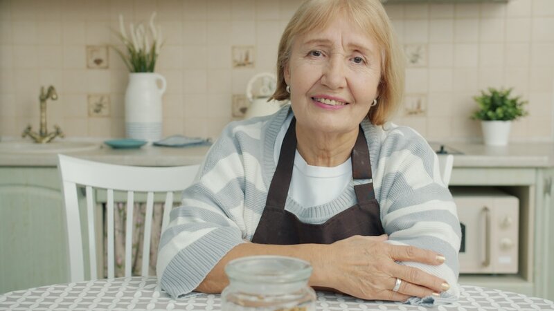 An older woman sitting calmly at her kitchen table at home