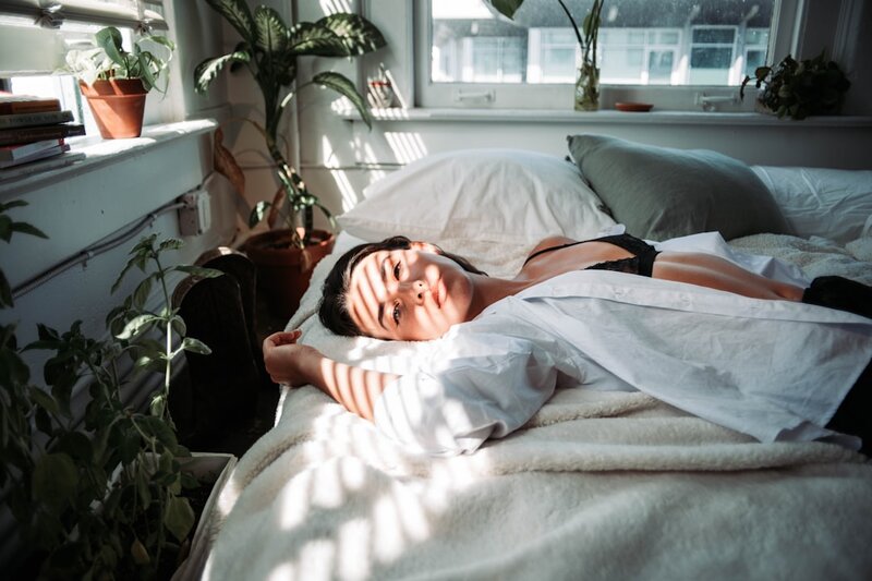 A woman resting peacefully in bed in soft morning light