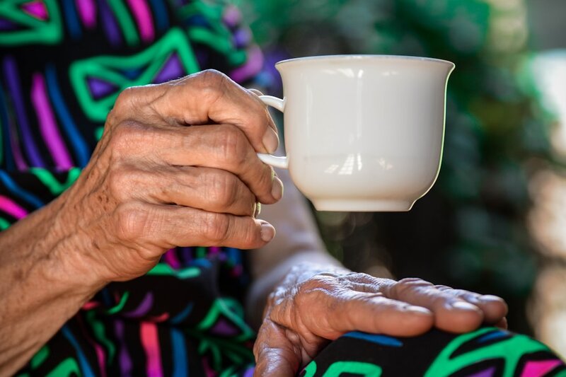 An older person's hands holding a cup of tea