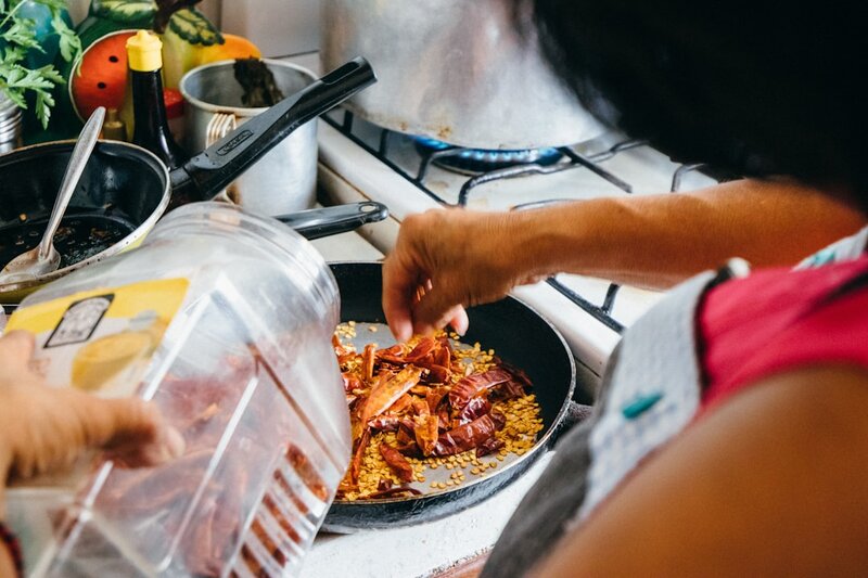 A woman cooking food in a pan on the stove