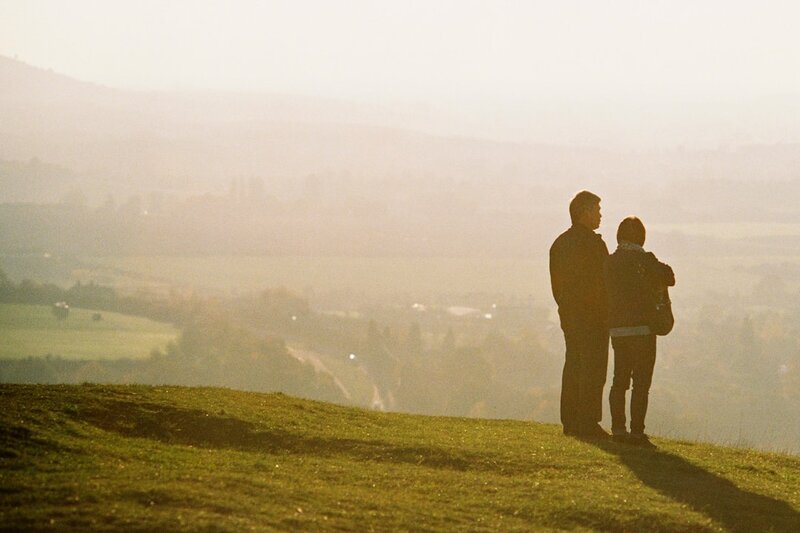 Two people standing on a hillside looking out over a hazy Irish valley at sunrise