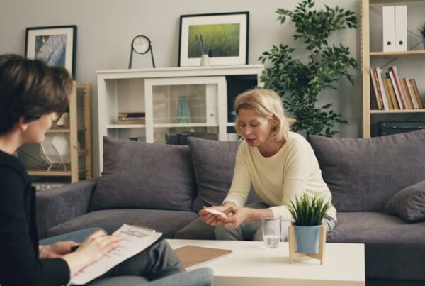 An older woman in conversation at home with a professional taking notes