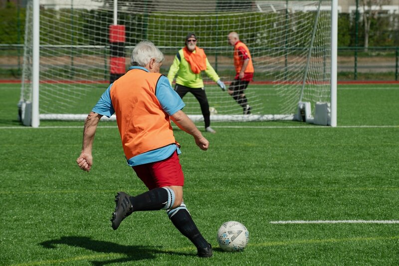 Older men playing walking football on an all-weather pitch
