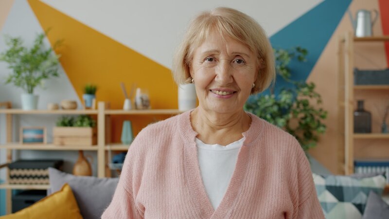 An older woman sitting at home in her living room, smiling