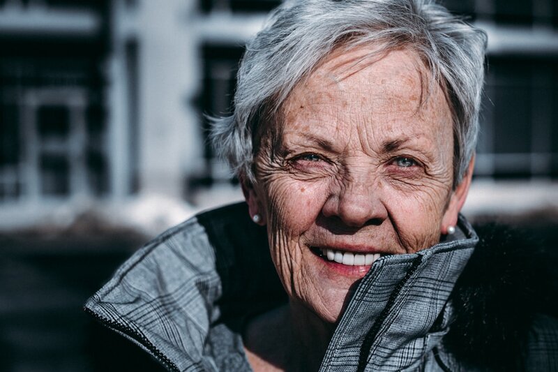 An older woman smiling warmly outdoors