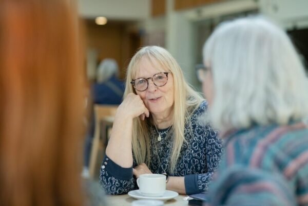 Two older women in conversation over a cup of tea
