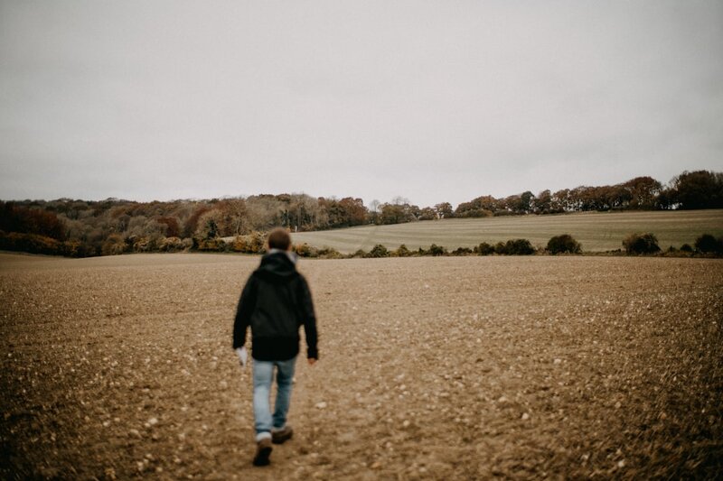 A man in a dark jacket walking across an open field